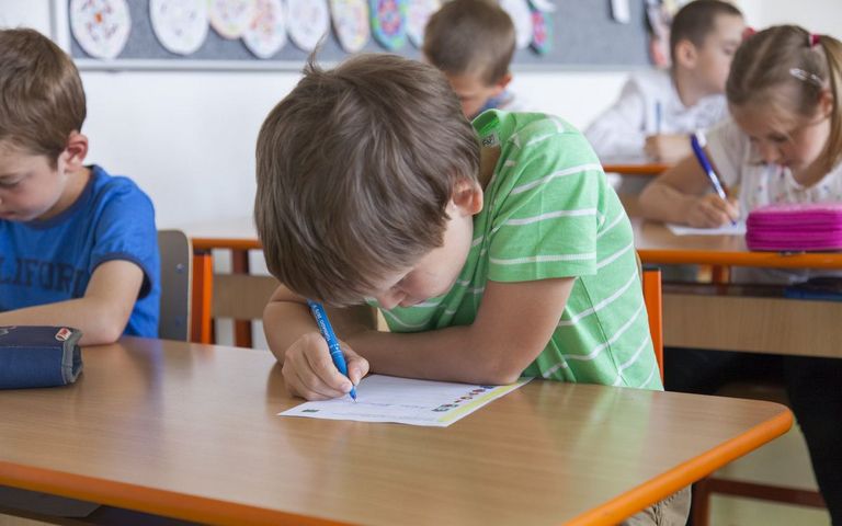 Schreibendesr Junge in einer Schulklasse. 