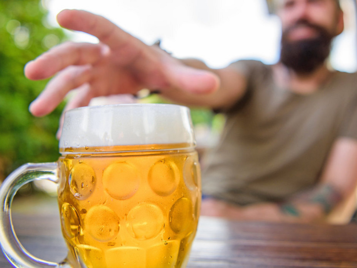 Ein Mann greift nach einem Bierglas.