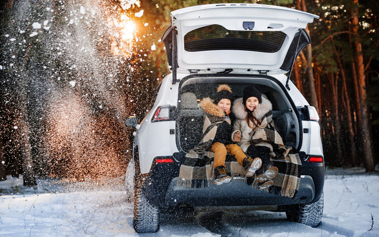 Zwei Kinder im Fonds eines Autos, das im Schnee steht. Foto: Olha - stock.adobe.com