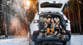 Zwei Kinder im Fonds eines Autos, das im Schnee steht. Foto: Olha - stock.adobe.com