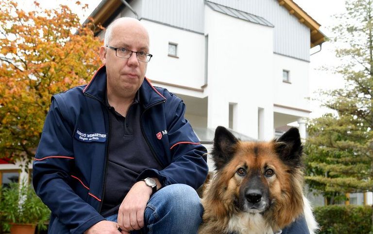 Ein Mann und ein Hund vor einem Gebäude