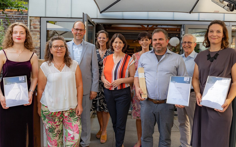 Mehrere Personen stehen nebeneinander und der Preisträger sowie die Finalistinnen halten Urkunden in der Hand. Foto: Jansen