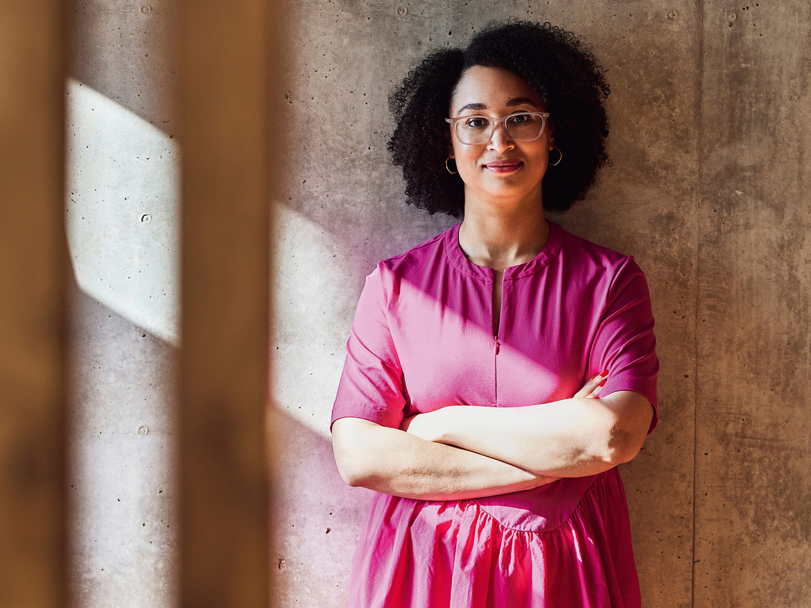 Sara Weber steht mit verschränkten Armen vor einer Wand und schaut in die Kamera. Foto: Maya Claussen