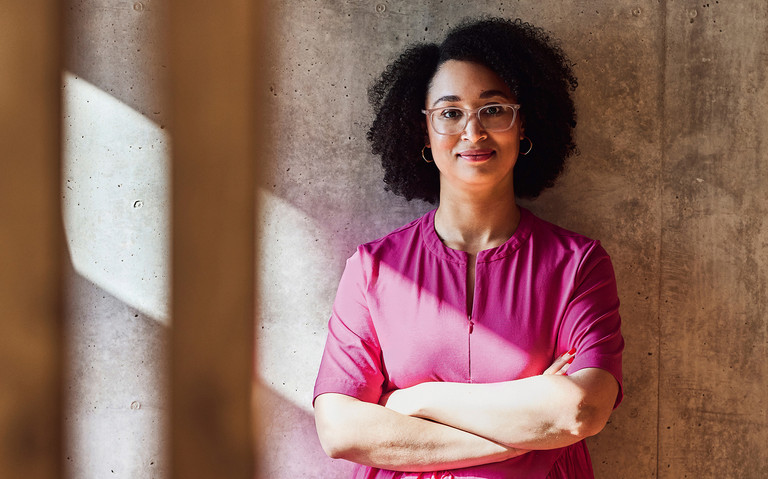 Sara Weber steht mit verschränkten Armen vor einer Wand und schaut in die Kamera. Foto: Maya Claussen