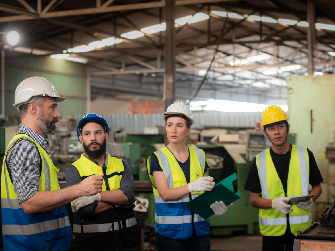 Produktionsteam bei einer Arbeitsbesprechung in der Fertigungshalle. Foto: pornchai - stock.adobe.com