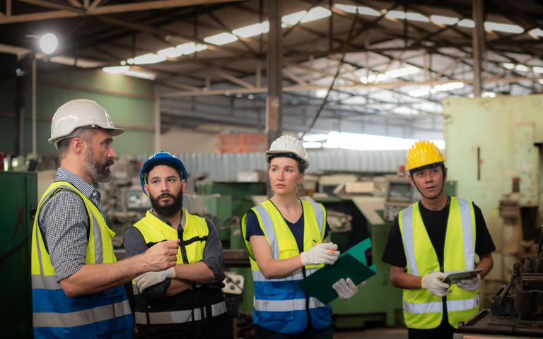 Produktionsteam bei einer Arbeitsbesprechung in der Fertigungshalle. Foto: pornchai - stock.adobe.com