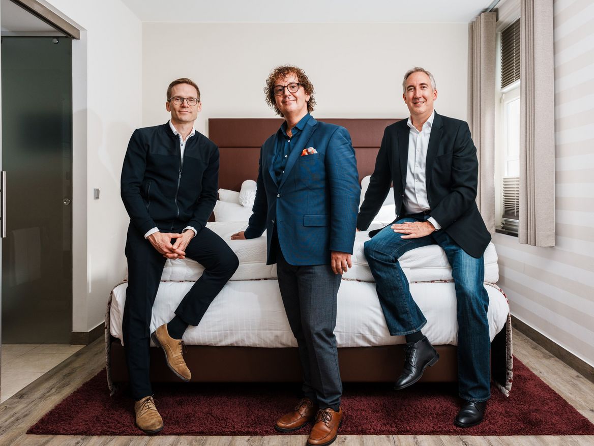 Drei Männer sitzen auf einem Bett