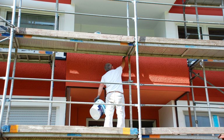 Ein Handwerker streicht eine Hauswand