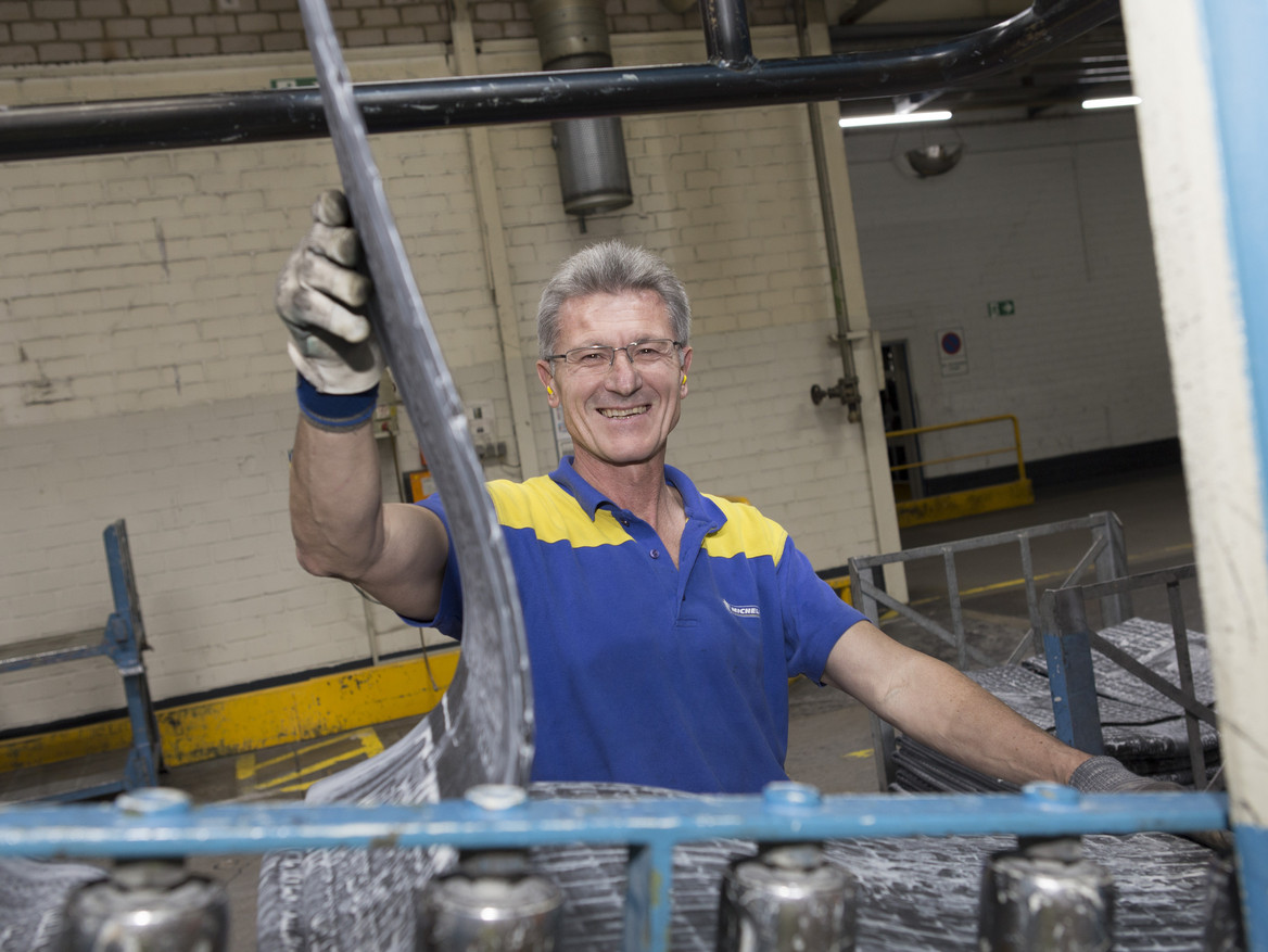 Ein älterer Mitarbeiter steht bei Michelin an einer Maschine.