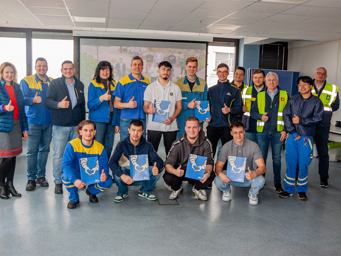 Die ehemaligen Azubis von Michelin in Bad Kreuznach sowie ihre Gratulanten und Ausbilder posieren für ein Gruppenfoto, alle zeigen Daumen nach oben und halten ihre Zeugnisse. Foto: Ulrike Dalheimer/Michelin