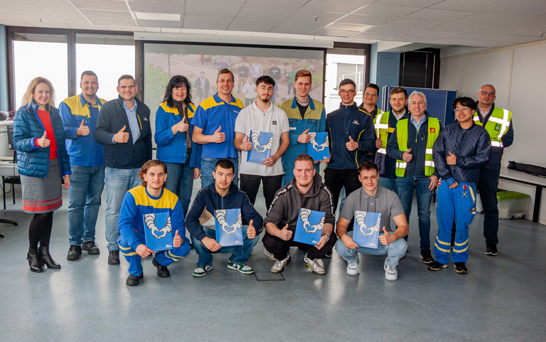 Die ehemaligen Azubis von Michelin in Bad Kreuznach sowie ihre Gratulanten und Ausbilder posieren für ein Gruppenfoto, alle zeigen Daumen nach oben und halten ihre Zeugnisse. Foto: Ulrike Dalheimer/Michelin