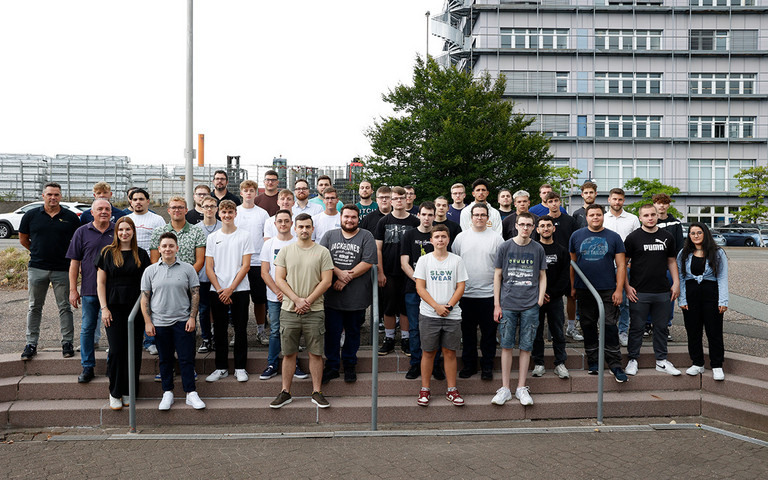 Viele junge Menschen stehen mit zwei Ausbildern auf einer Treppe nebeneinander. Quelle: profine 