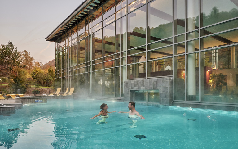 Außenbereich der Vulkaneifel-Therme in Bad Bertich, in dem ein Mann und eine Frau schwimmen. Foto: CC BY-SA Rheinland-Pfalz Tourismus GmbH/Florian Trykowski