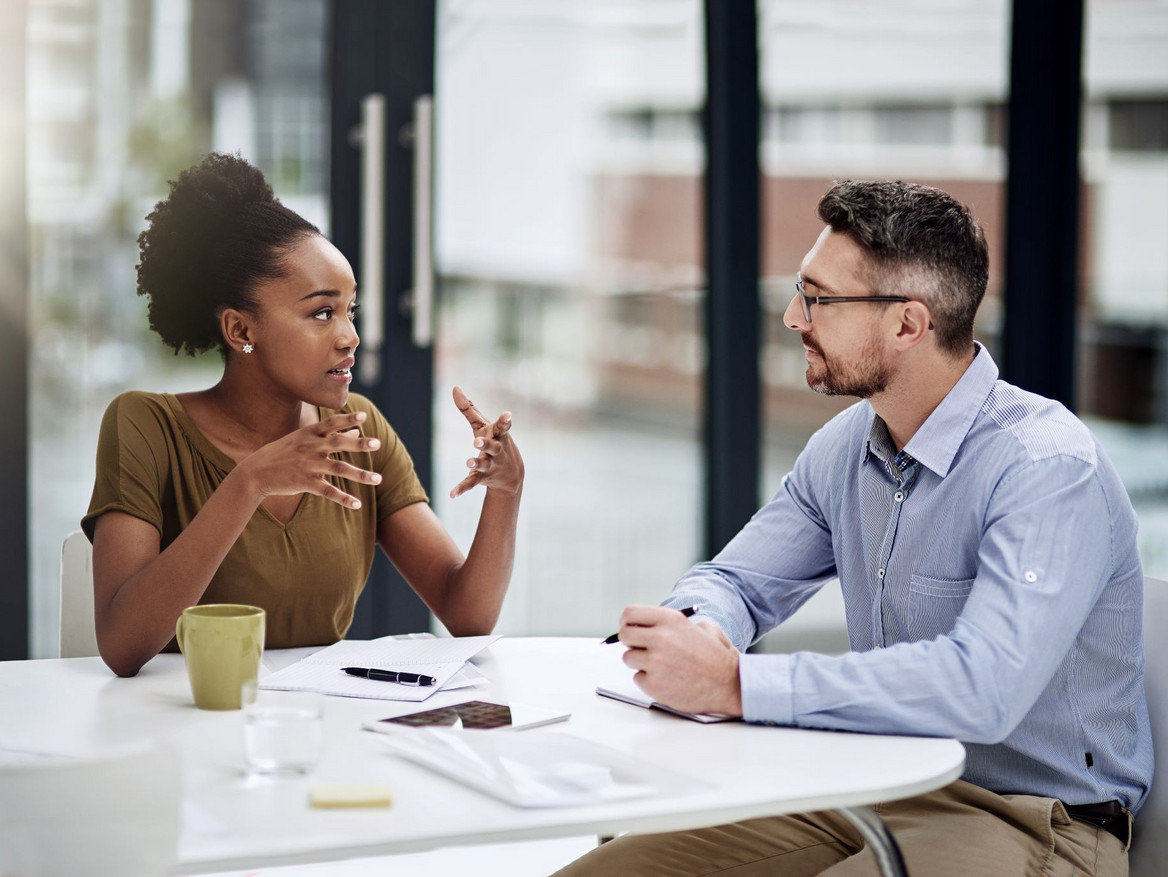 Zwei Berufstätige in einem konstruktiven Dialog am Arbeitstisch. Foto: Katleho Seisa peopleimages.com - stock.adobe.com