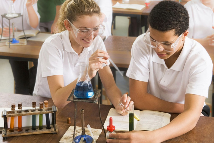 Schülerin und Schüler beim Chemie-Experiment im Klassenraum. Foto: Storyblocks