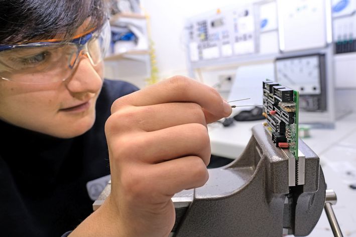 Feinarbeit: Geschickt setzt Azubi Fabian Becker elektronische Bauteile in eine Leiterplatte ein.
